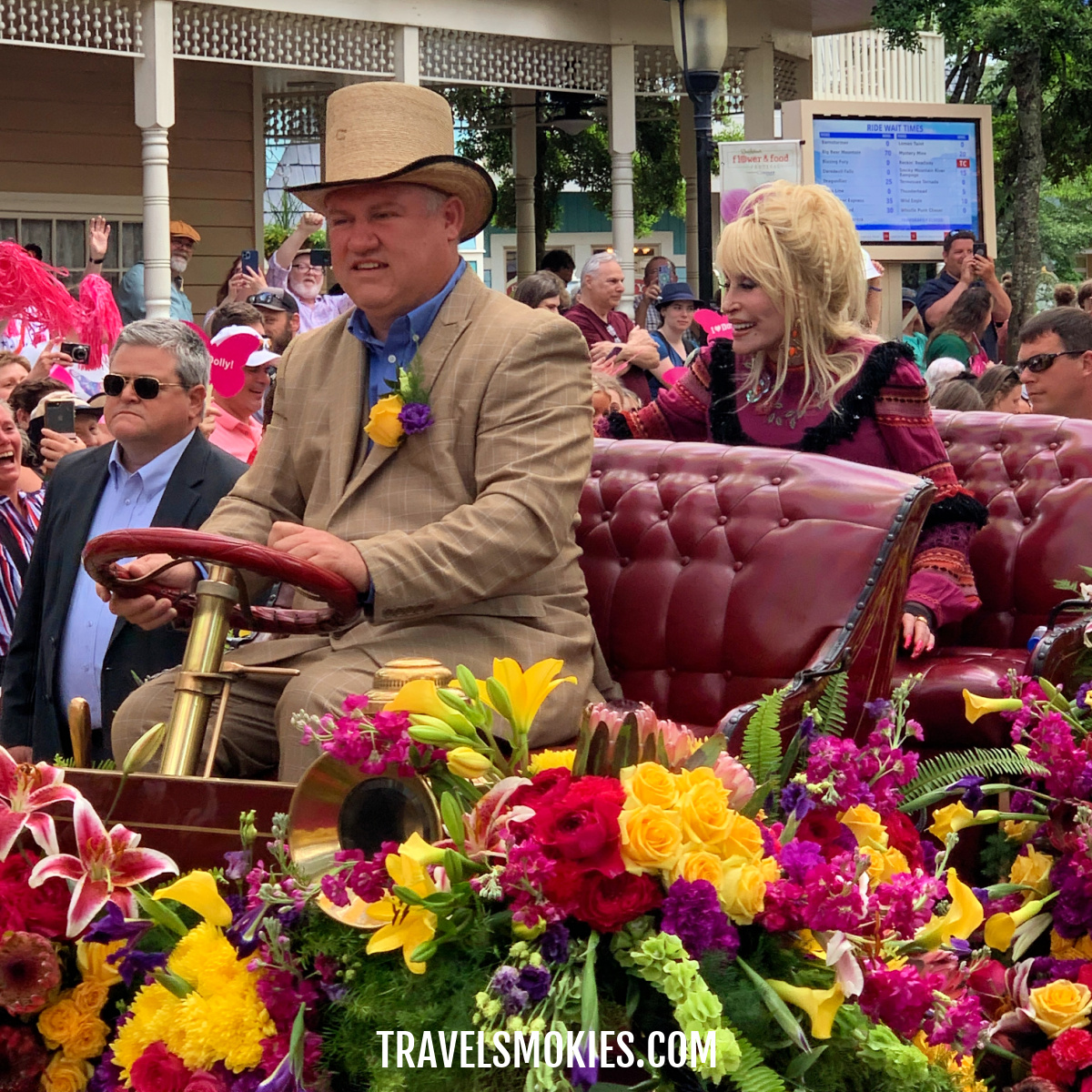 Dolly Parton riding in a parade through Dollywood Theme Park waving at fans